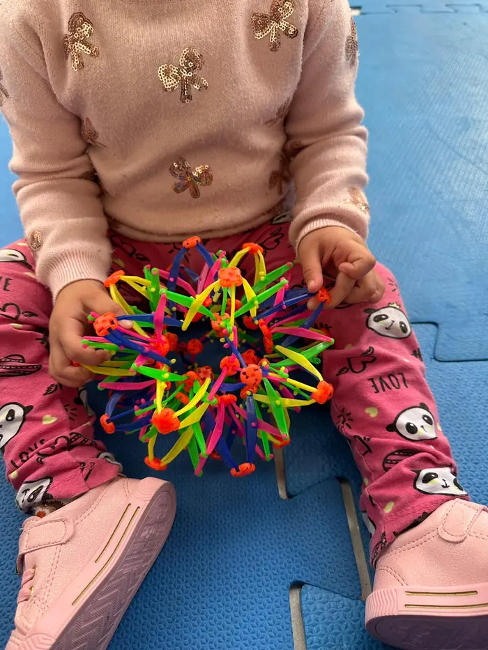 Criança manipulando uma bola expansível colorida durante a aula