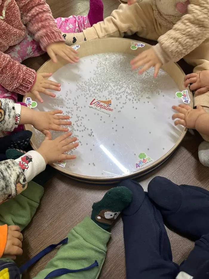Mãos de bebês explorando um tambor de vibração translúcido