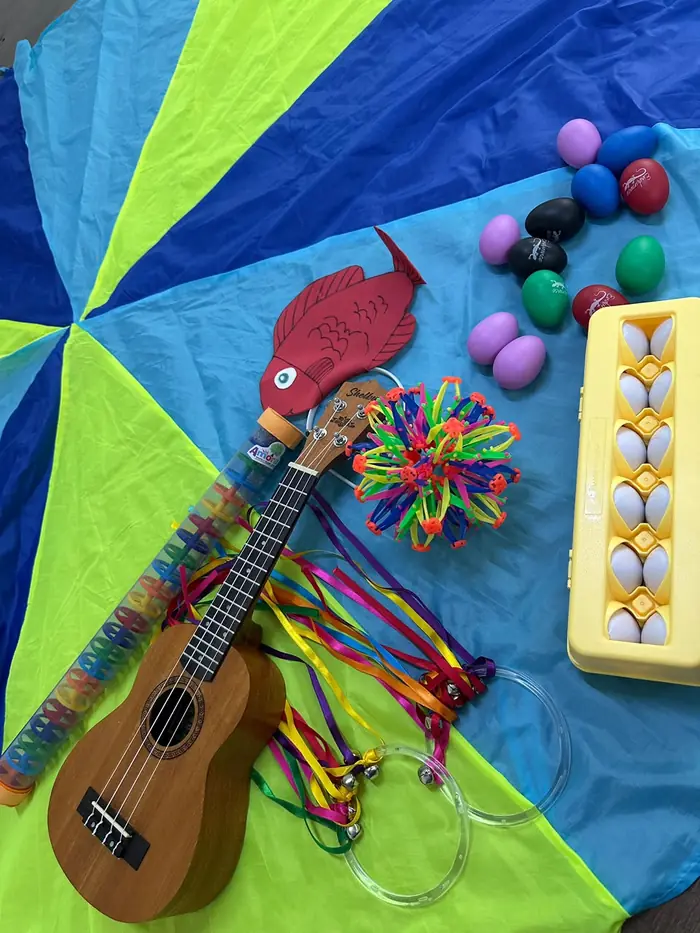 Instrumentos e materiais de musicalização dispostos sobre um paraquedas colorido